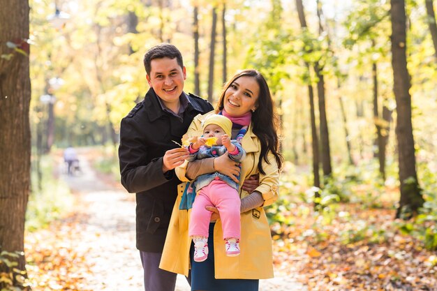 Love, parenthood, family, season and people concept - smiling couple with baby in autumn park