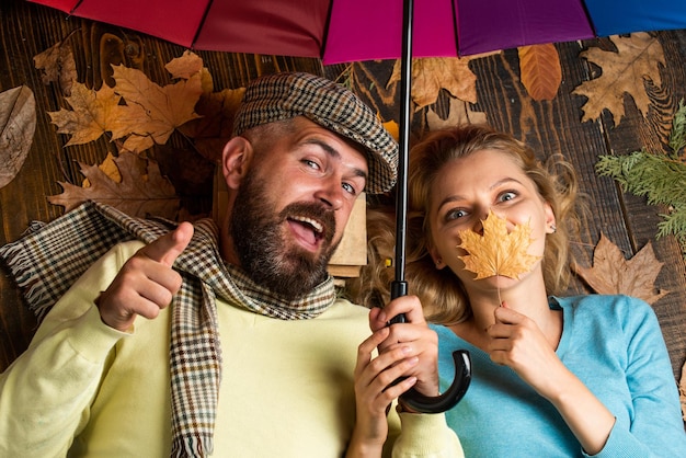 Love and people concept happy couple under colorful umbrella family relax among autumn leaves Happy to be around Good mood at any weather staying positive and optimistic