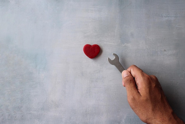 Love romantic valentines day concept Top view image of hand holding spanner and red heart Copy space