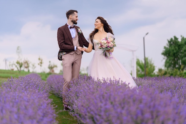 Love story of brides couple walking in lavender meadow