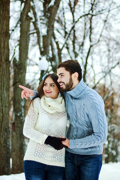 Love story. funny couple in snowy park. young man, woman in warm sweaters. Family winter holiday