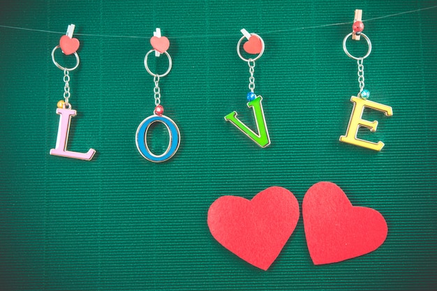 Love text message with 2 red hearts hang on green background, valentine concept