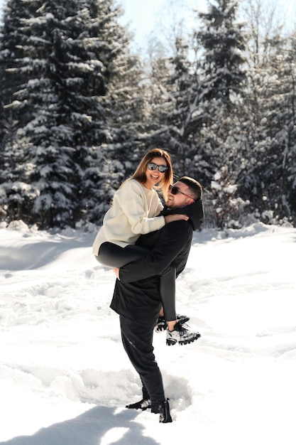 Love and vacation concept  happy couple hugging and laughing outdoors in wintercouple in nature