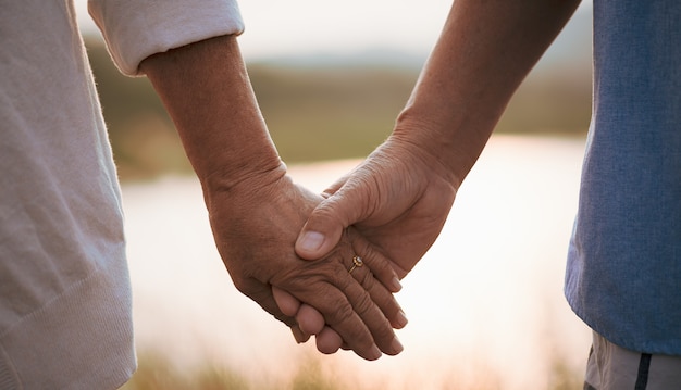 Love and Valentine day concept. A happy senior couple holding hand  during sunset