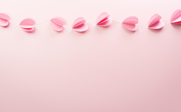 Love and Valentine's day concept made from pink paper hearts on pastel background