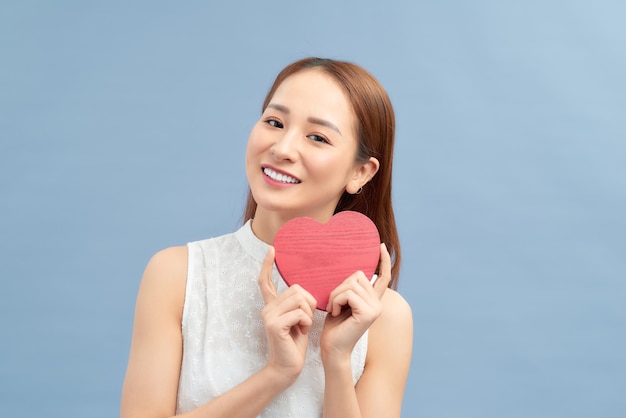 Love and valentines day woman holding heart smiling cute and adorable isolated on blue background