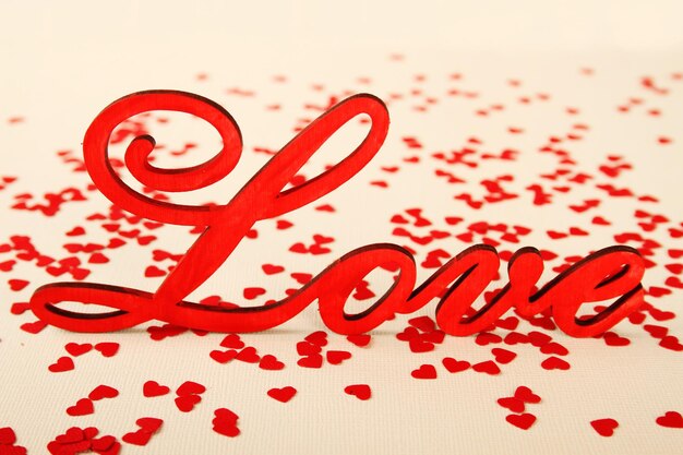 Love wooden letters on the background of the little red hearts