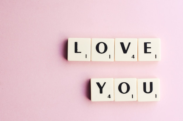 LOVE word on wooden cubes on a pink background.