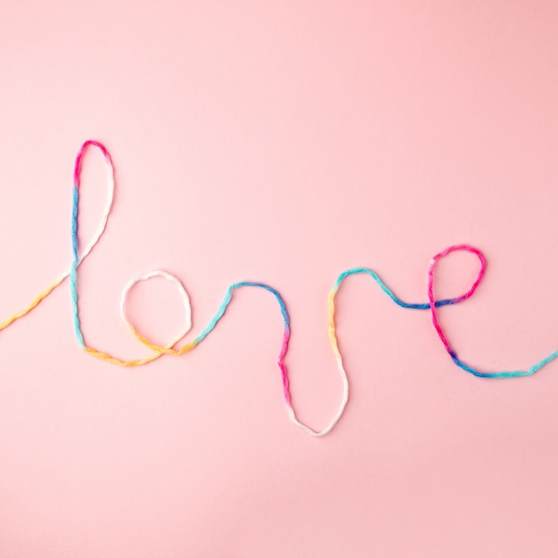 Love word written with woolen thread lettering, concept and background for Valentine's Day