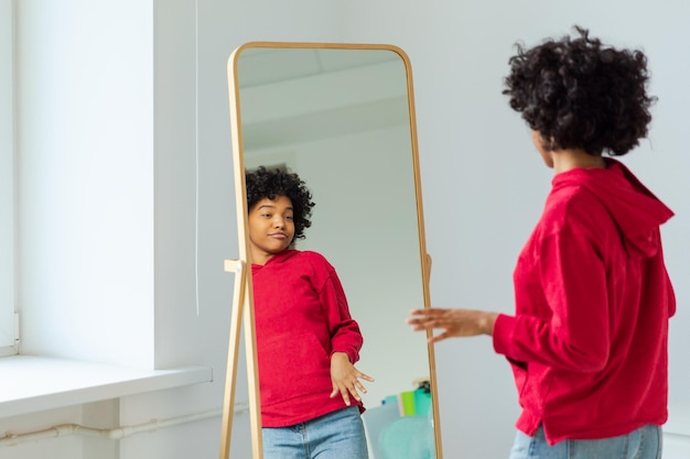 Love yourself Beautiful young smiling african american woman dancing enjoying her mirror reflection Black lady looking at mirror looking confident and happy Self love concept