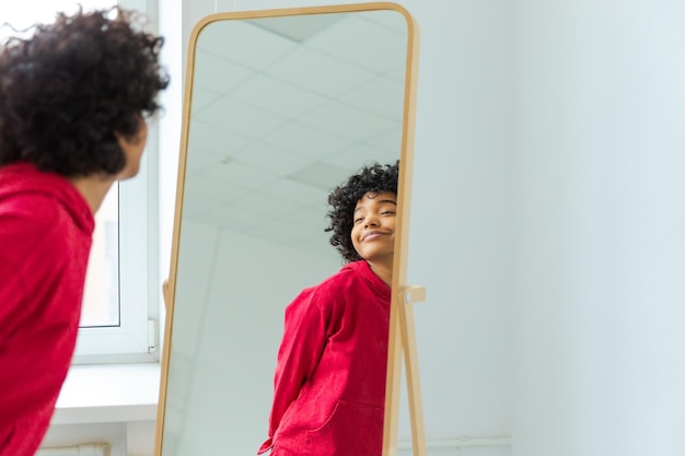 Love yourself Beautiful young smiling african american woman dancing enjoying her mirror reflection Black lady looking at mirror looking confident and happy Self love concept