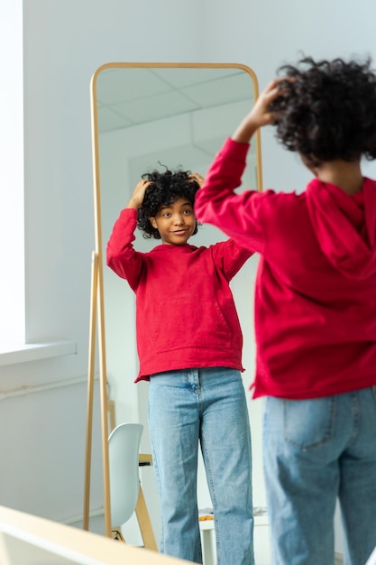 Love yourself beautiful young smiling african american woman dancing touching curly hair enjoying he