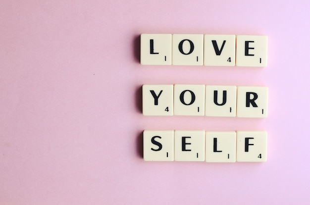 LOVE YOURSELF word on wooden cubes on a pink background