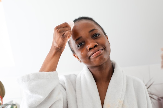 Lovely african girl massaging face with rose quartz gua sha