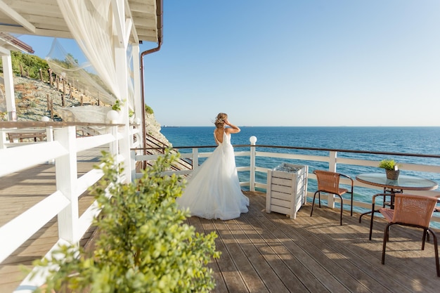 Lovely bride in white wedding dress posing near the sea with beautiful background