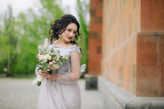 Lovely bridesmaid with bridal bouquet next to the church before the ceremony