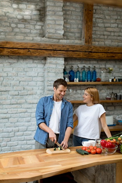 Lovely cheerful couple cooking dinner together and having fun at rustic kitchen