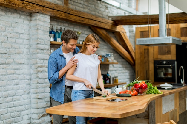 Lovely cheerful couple cooking dinner together and having fun at rustic kitchen