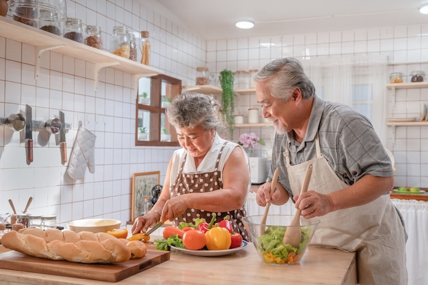 lovely couple asian elder happy and smiling cooking salad together for breakfast at home kitchen