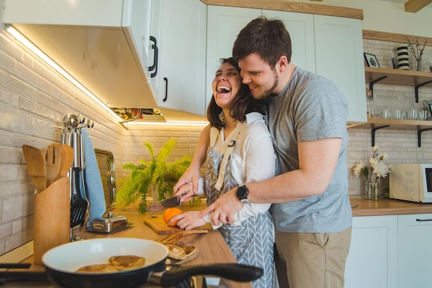 Lovely couple hugging on the kitchen while cooking breakfast