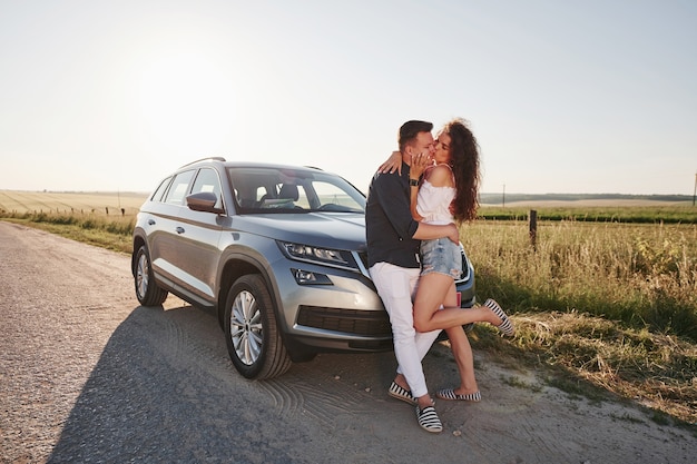 Lovely couple near their new modern car at weekend time.