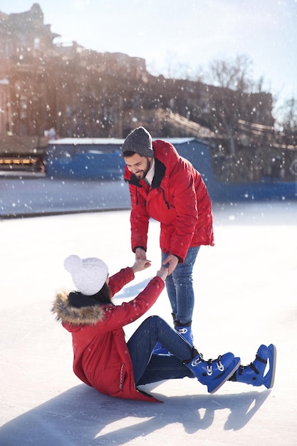 Lovely couple spending time together at outdoor ice skating rink