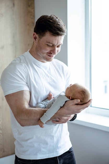 Lovely dad hugging his cute small child Handsome man holding newborn