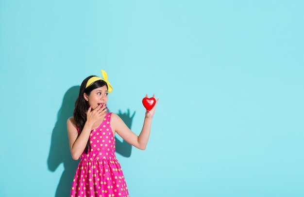 lovely elegant girl looking at heart shaped in blue background and feeling surprised.