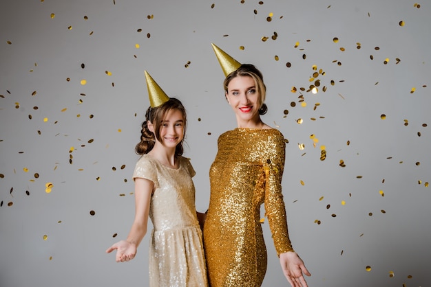 Lovely and elegant mother and daughter in beautiful fashionable dresses