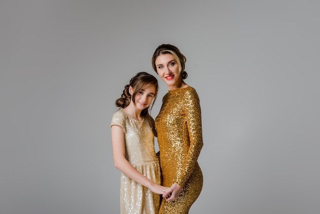 Lovely and elegant mother and daughter in beautiful fashionable dresses