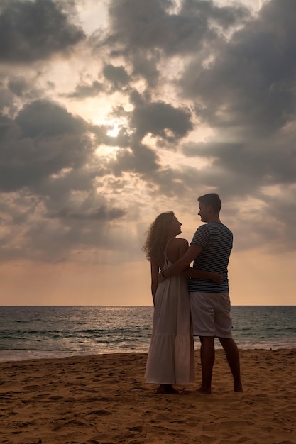 Lovely family couple holding hands look at each other at ocean sunset background Man and woman in casual clothes walking together sandy beach outdoor