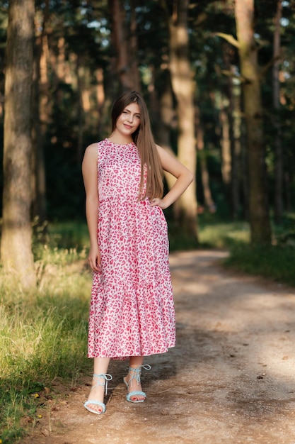 Lovely girl in pink summer dress on forest road