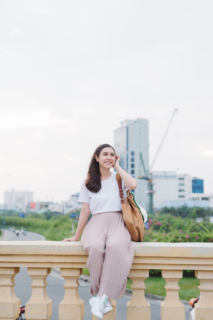 Lovely girl sitting over the bridge railing . Enjoying the beauty of the river. Sitting alone and looking at such a beauty arises dreams and thoughts in her mind.