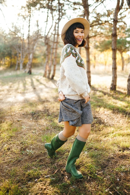 Lovely girl with a beautiful smile at sunset in the forest The girl is dressed with a hat