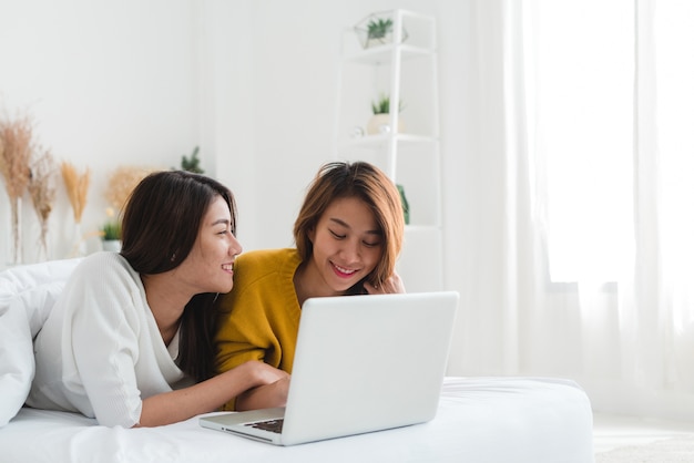 Lovely lesbian couple together concept. Couple of young women using computer laptop on bed.