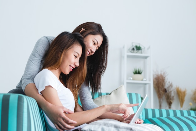 Lovely lesbian couple together concept. Couple of young women using tablet in living room