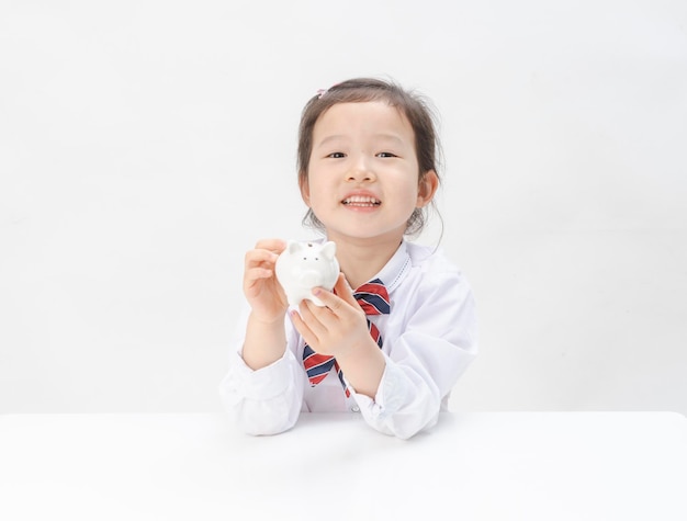 The lovely little girl has a piggy bank in her hand