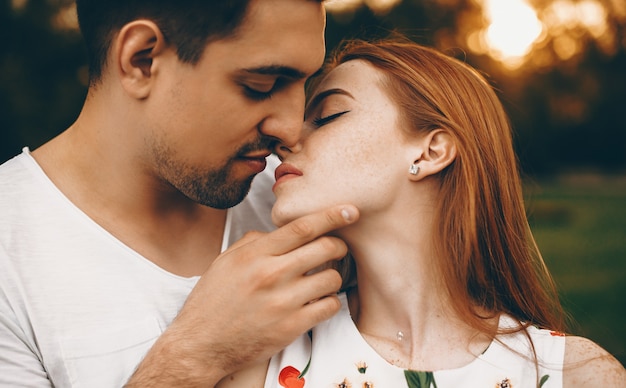 Lovely man and woman kissing against sunset outdoor