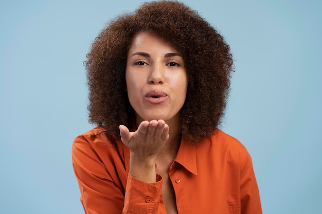 Lovely romantic african girl looking at camera and air kissing over palms hands