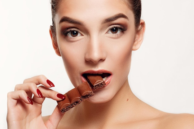 Lovely smiling teenage girl eating chocolate