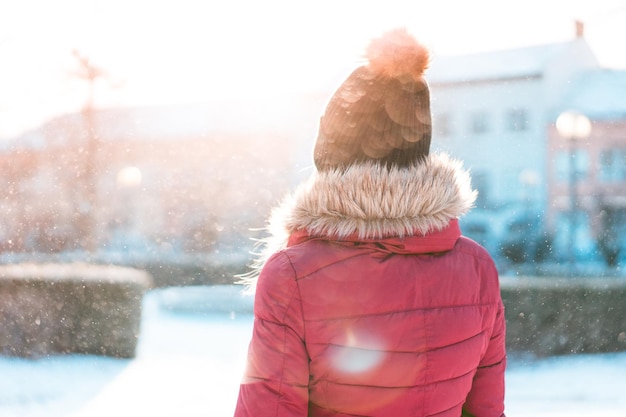 Lovely teen girl in pink knitted glove, hats and scarf, fur hooded jacket winter walks in the park.