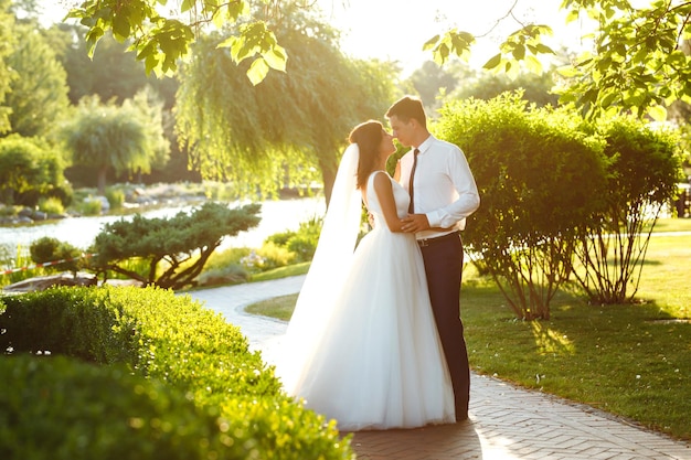 Lovely wedding couple at sunset Bride groom in wedding attire with bouquet of flowers Romantic