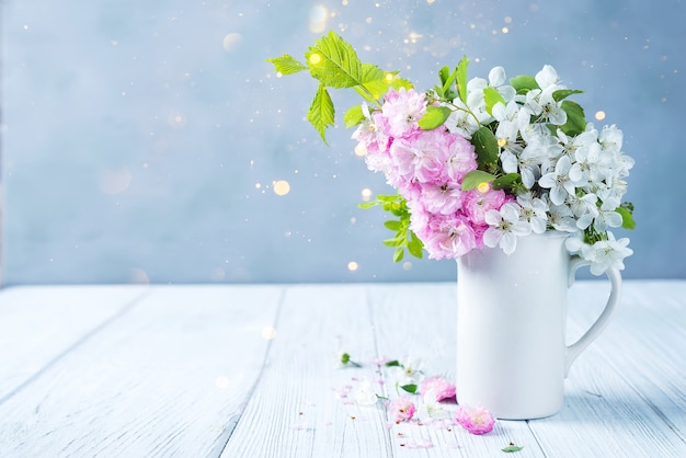 Lovely wild flowers bunch in ceramic vase on table in wooden background 