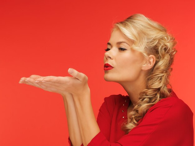 lovely woman in red dress blowing something on the palms of her hands