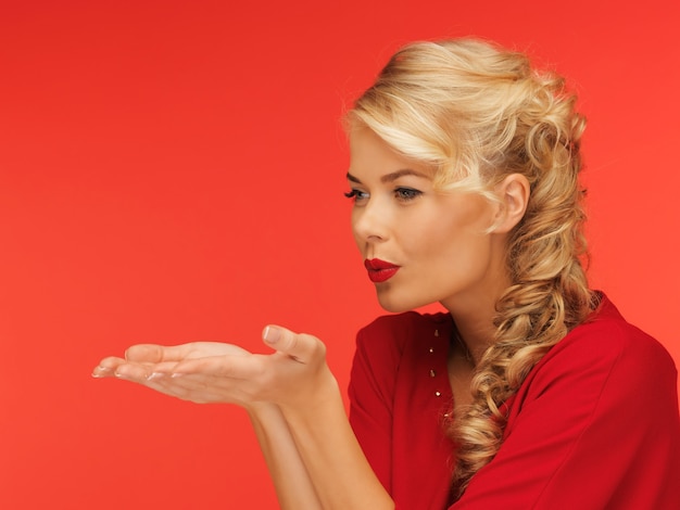 lovely woman in red dress blowing something on the palms of her hands