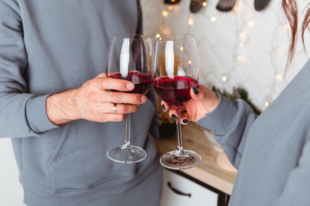 Lovely young couple sitting floor kitchen drink wine in glasses, garlands home cosy interior