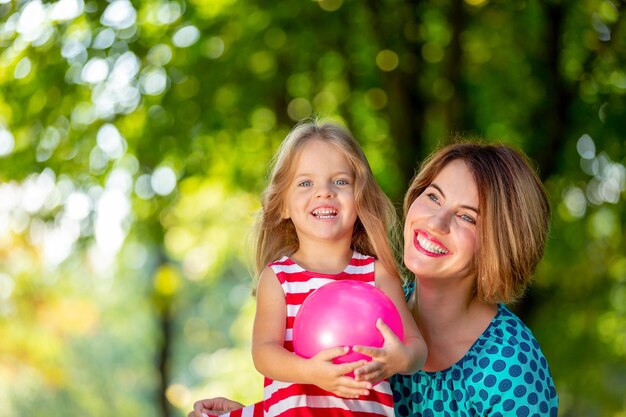 Lovely young mom and daughter in warm sunny summer day Happy family mother and child little daughter playing and walking in the Park and enjoying the beautiful nature