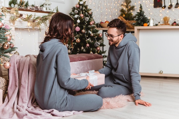 Lovely young romantic couple sitting open gifts presents garlands home cosy interior atmosphere