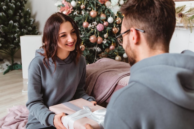 Lovely young romantic couple sitting open gifts presents garlands home cosy interior atmosphere