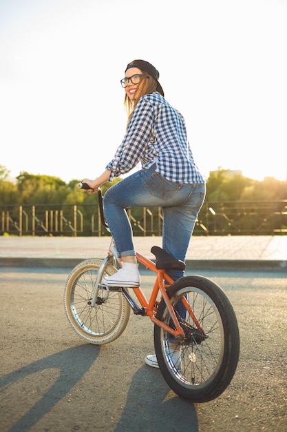 Lovely young woman in a hat riding a bicycle on city background in the sunlight outdoor Active people